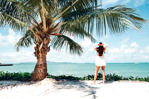 Preview: A woman enjoying a beach scene with hands on head