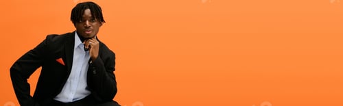 Preview: Handsome young man stylishly posed against a vibrant orange background expressing confidence