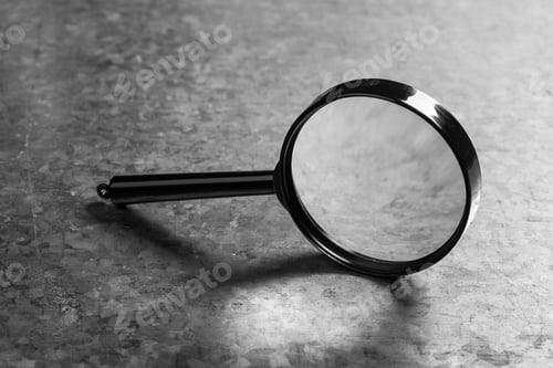 Preview: Magnifying glass resting on a gray surface in a well-lit room during daytime hours