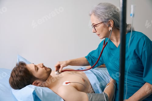 Preview: Experienced elderly doctor listens with a stethoscope to young patient