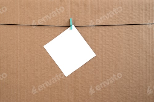 Preview: White blank card on rope on a brown cardboard background