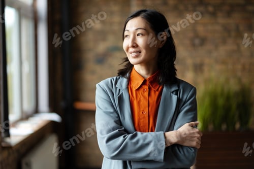 Preview: Confident asian businesswoman smiling and looking away in office