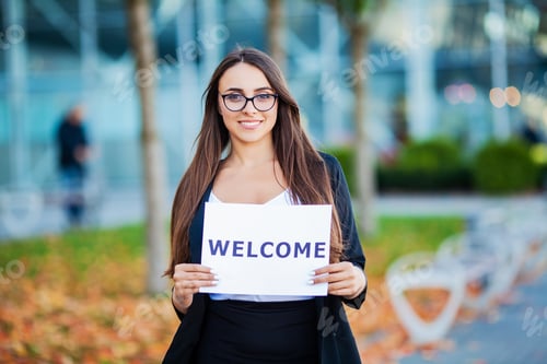 Preview: Businesswoman with long Hair Holding a sign Board with a Welcome has Airport Background