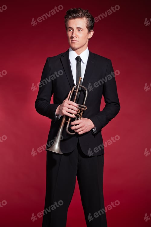 Preview: Retro Fifties Trumpet Player Wearing Black Suit. Holding His Trumpet. Red Background.