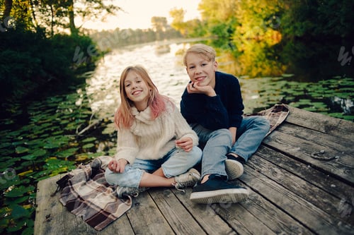 Preview: Happy Children Sitting on a Dock by a Lake