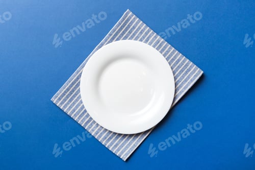 Preview: Top view on colored background empty round white plate on tablecloth for food.