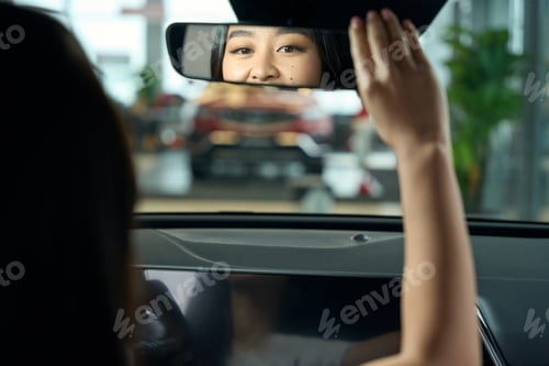 Preview: Charming young woman is sitting behind the wheel of car