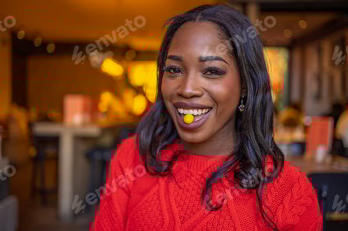 Preview: Playful woman holding candy in mouth at restaurant