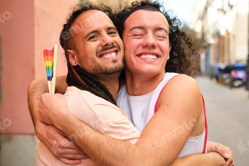Preview: Two men hug each other while holding rainbow fan during Pride Parade.