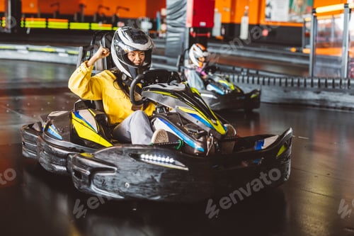 Preview: excited asian teenage woman raising fist high at kart race