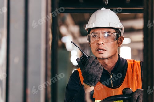 Preview: Male worker talking on walkie-talkie while driving forklift
