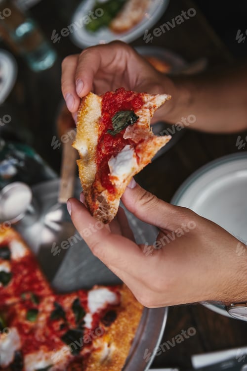 Preview: cropped shot of man eating delicious pizza at restaurant