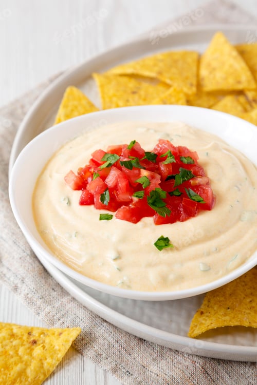 Preview: Homemade cheesy dip in a bowl, yellow tortilla chips, side view. Closeup.