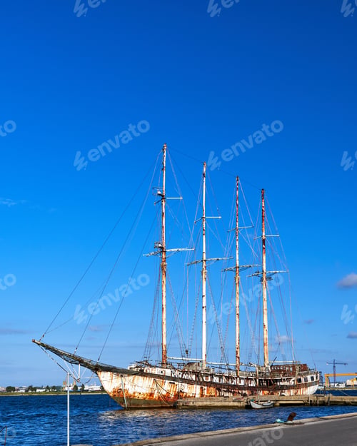Preview: Vertical of an old rusty sailboat at the docks against the blue cloudless sky