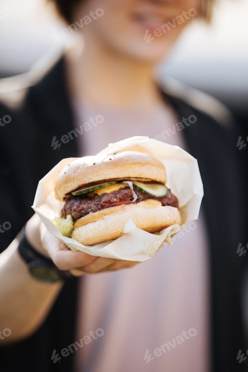 Preview: Girl enjoying takeaway burger in park