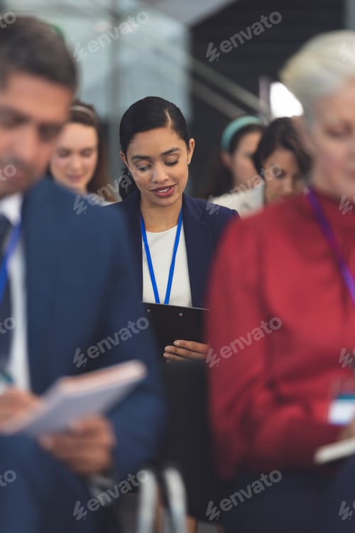 Preview: Businesswoman writing on notepad in a business seminar in office building