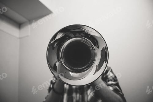 Preview: Grayscale shot of a person playing the trumpet with the bell side facing the camera