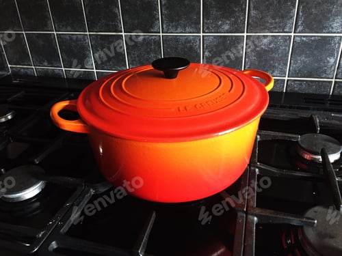 Preview: An orange Le Creuset casserole pot on a cooker hob or stove