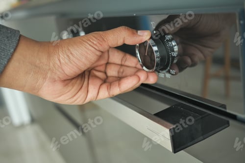 Preview: men hand setting temperature control on oven.