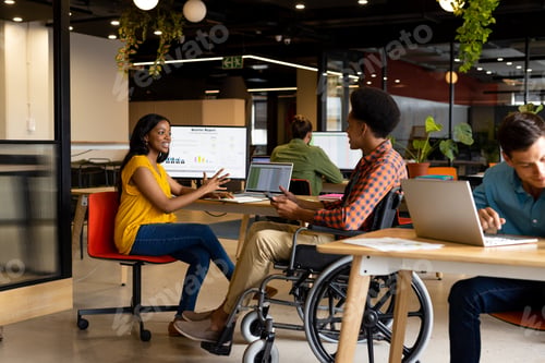 Preview: Happy diverse male and female colleagues in discussion using tablet in casual office meeting