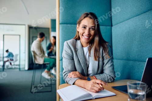 Preview: Happy female entrepreneur working in the office and looking at camera.