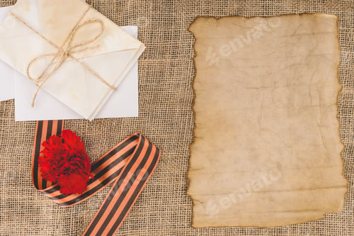 Preview: top view of st. george ribbon, carnation, old empty paper, stack of letters
