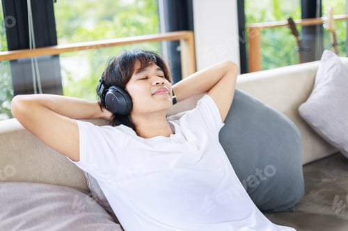Preview: A man listening to music with wireless headphones in living room. People leisure activitiesLifestyle