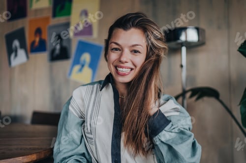 Preview: Adorable caucasian woman looks at camera toothy smiles sits at cafe. Portrait of hispanic girl