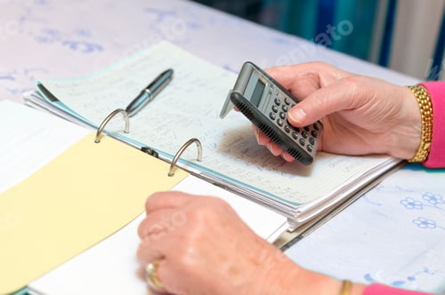 Preview: Closeup shot of a person doing taxes while using a calculator