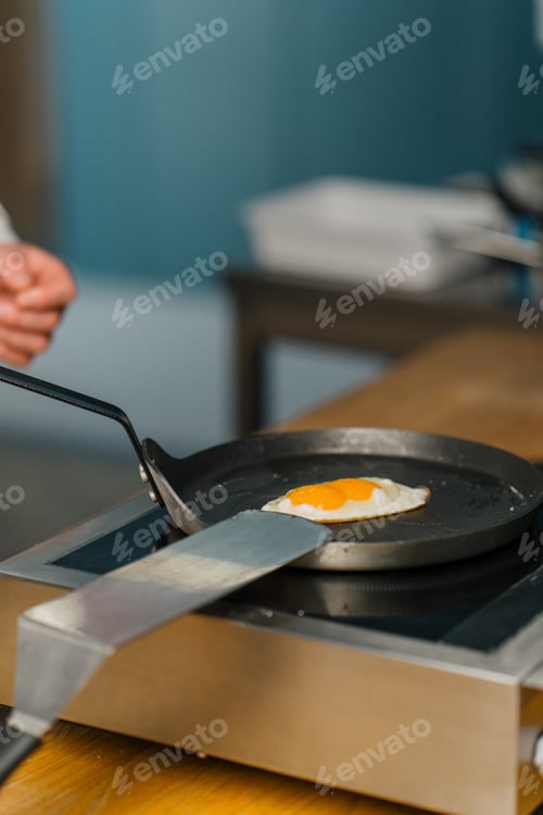 Preview: Professional kitchen chef frying eggs in a pan