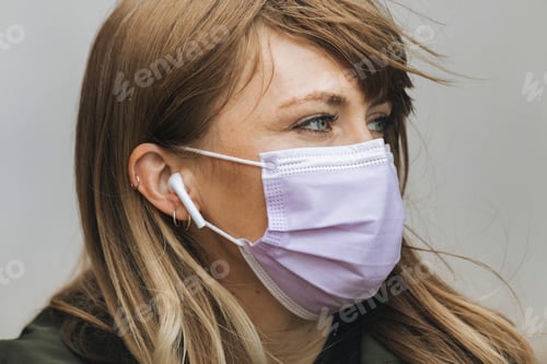 Preview: Woman in a face mask listening to music during coronavirus pandemic