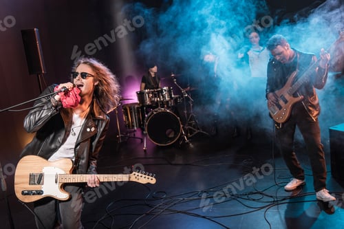 Preview: Male singer with microphone and rock and roll band performing hard rock music on stage