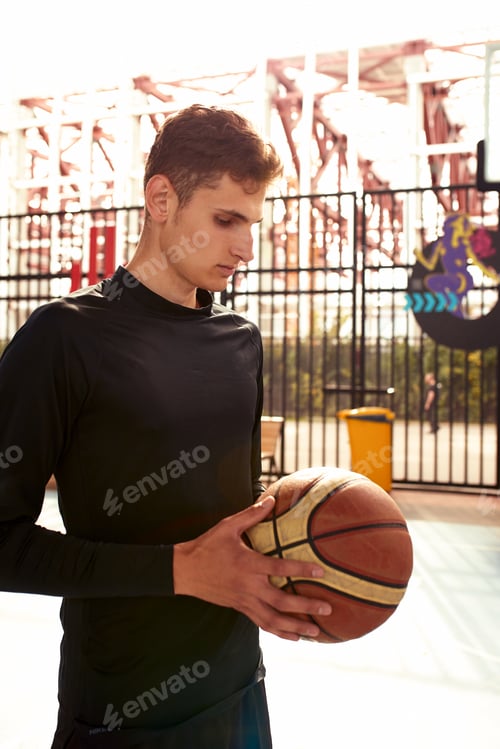 Preview: Young man with a basketball in his hands on the city basketball court