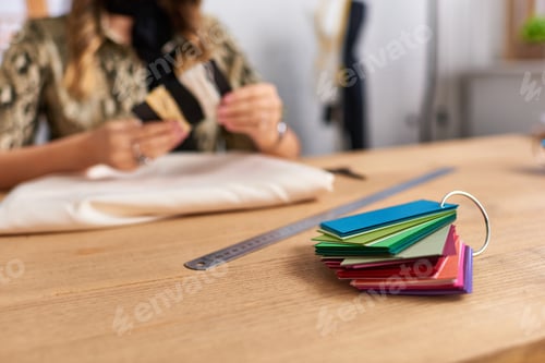 Preview: selective focus of color samples near cropped designer and sewing supplies in fashion atelier