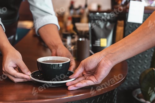 Preview: Close up of hands barista man serving coffee in coffee shop. male hands placing a cup of coffee