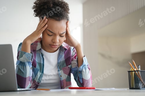 Preview: Tired african american teen girl suffer headache doing homework at laptop. Difficult elearning