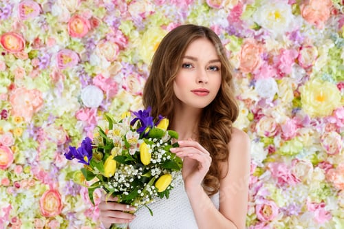 Preview: beautiful young woman with curly hair holding floral bouquet