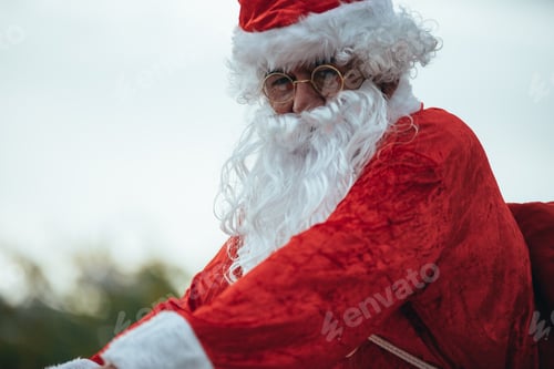 Preview: Santa Claus with gifts in the bicycle and his red suitcase on his back. Christmas time