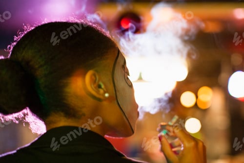 Preview: Rear view of young woman in nightclub smoking cigarette