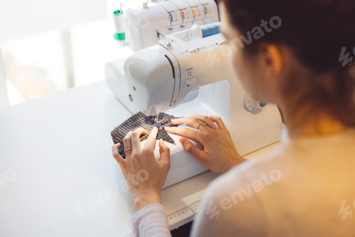 Preview: Unrecognizable woman sewing on a sewing machine. Woman learning how to use a sewing machine at home