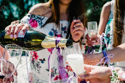 Preview: Girl pours champagne into glass. Beautiful happy stylish sexy young girls on sand beach. Glasses