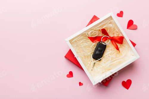 Preview: Black car key in a present box with a ribbon and red heart on colored background