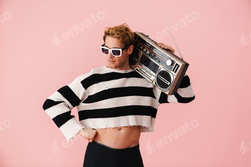 Preview: Ginger young man wearing sunglasses posing with retro tape recorder