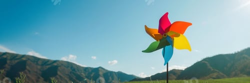 Preview: Multi-colored windmill, pinwheel in the background of green mountains and sky