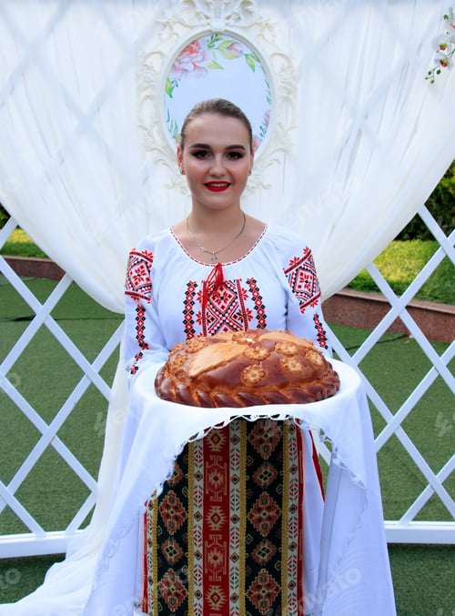 Preview: Vertical shot of a beautiful lady in a traditional costume holding a big homemade pie