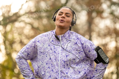 Preview: Healthy woman listening to music in the park, stretching and keeping fit
