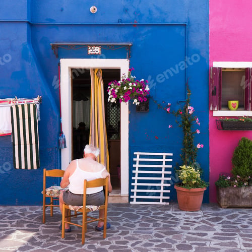 Preview: Mature man seated on a chair outside a bright and vibrant home.