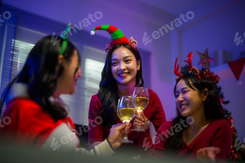 Preview: Asian women friends celebrating Christmas holiday party, smiling and toasting wine at home