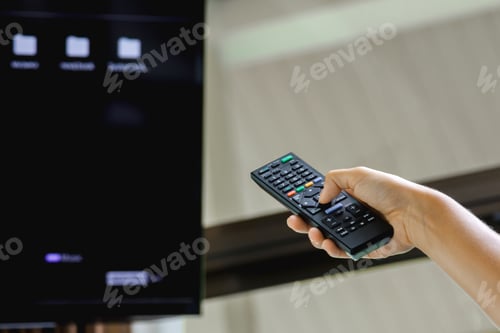 Preview: Female hand with TV remote control in the room