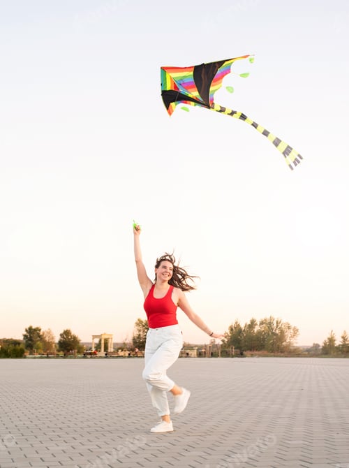 Preview: Active lifestyle. Happiness concept. Happy young woman running with a kite in a park at sunset